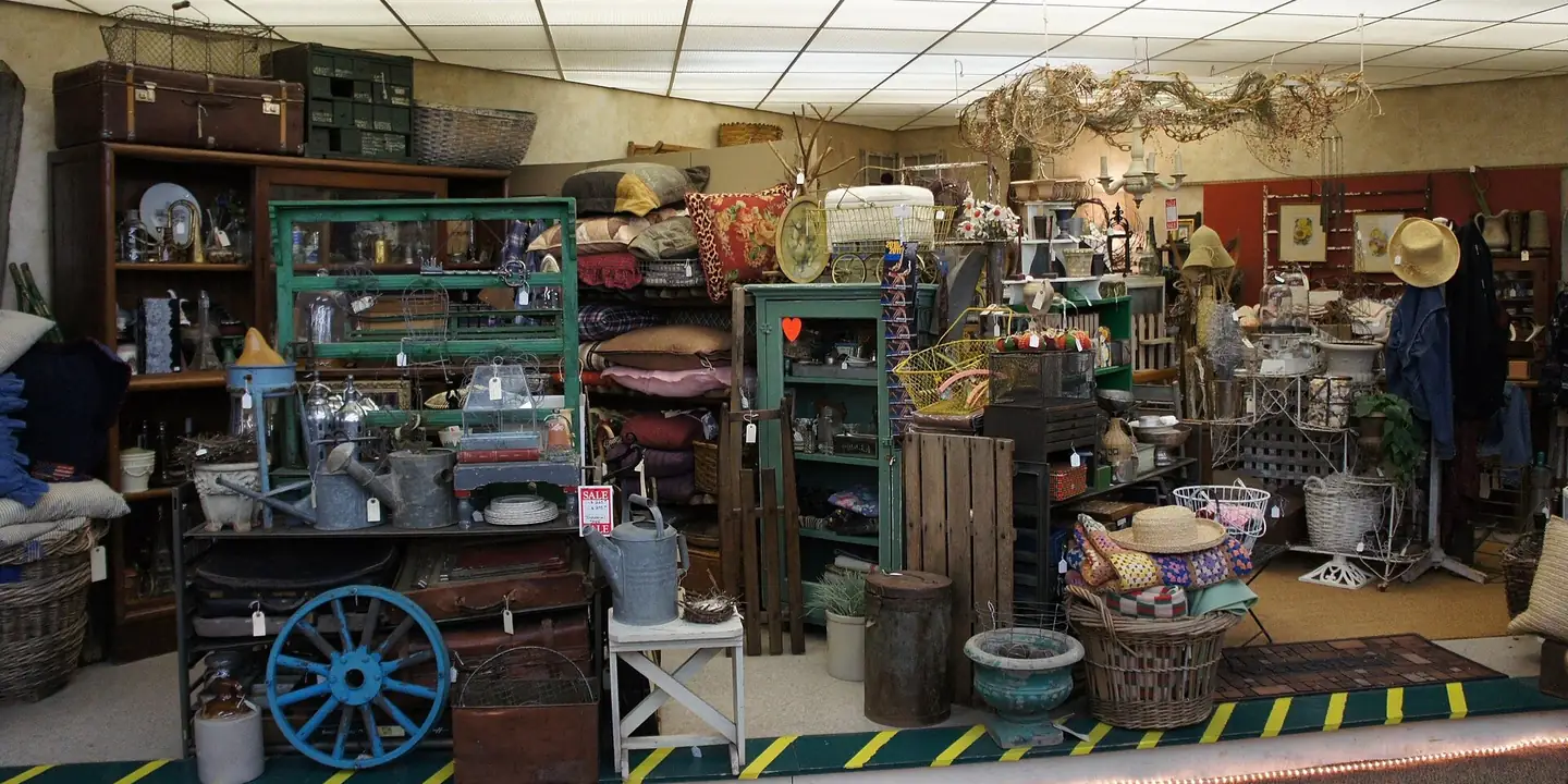 Dealer booths filled with furniture, crates, baskets and hats inside an antique mall