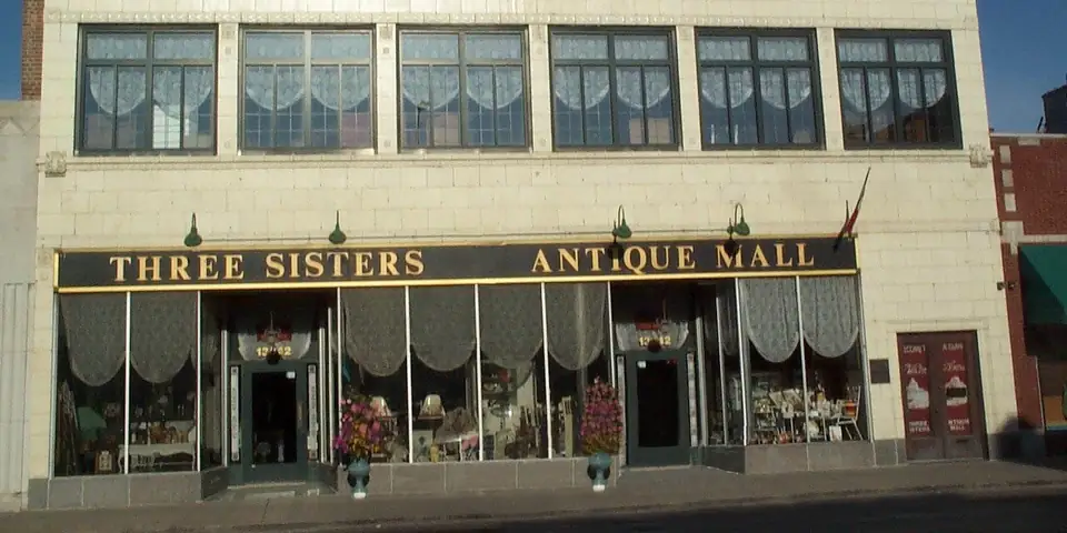 Cream terra cotta building with a Three Sisters Antique Mall sign