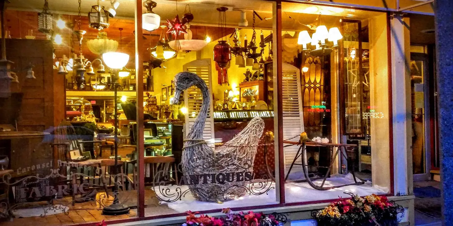 Glowing antique store window full of lamps and furniture at night
